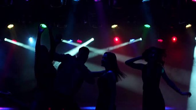 一群青少年在黑暗中的音乐会上跳舞。