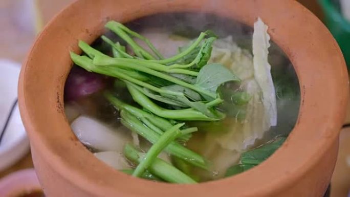 关闭烹饪泰国风味的Chim chum汤与蔬菜在粘土陶器与煮沸watar，泰国街头食品