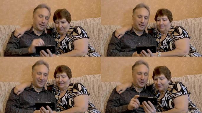 一名老年妇女和她的成年儿子正在智能手机上观看家人的照片。