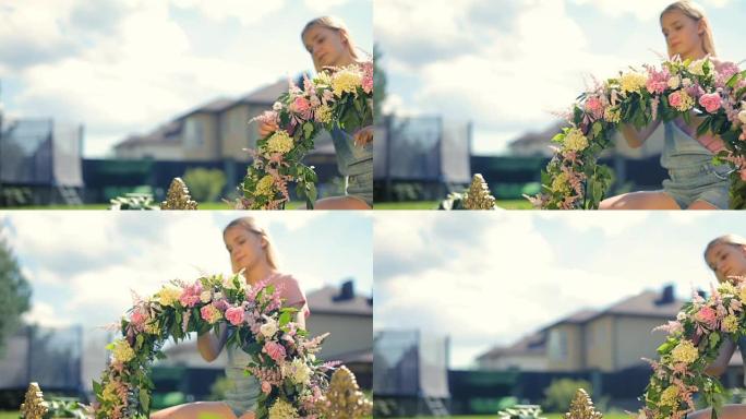 儿童课外活动弗洛里斯蒂克接待装饰课程 -- 漂亮的女模特金发微笑的女孩在户外翡翠草地上用花朵制作花卉