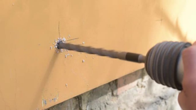 工人使用穿孔器在墙上开一个洞