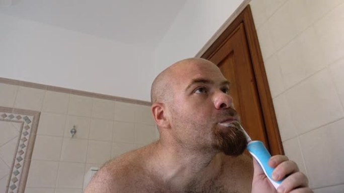 口腔卫生: 男人用电动牙刷刷牙