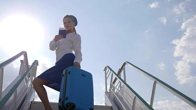 空姐在机场的飞机楼梯上手持手提箱和护照背光