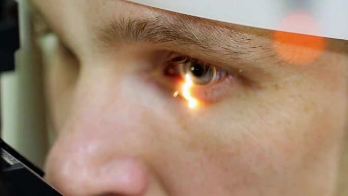 面部特写，在光学诊所，眼科实验室用非接触式眼压计做眼睛测试的人，咀嚼视力，眼压