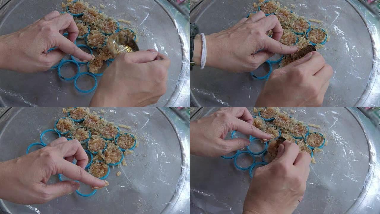 女性手将米饭和西瓜汁混合在模具中制成炒年糕。米饼是泰国的传统小吃。
