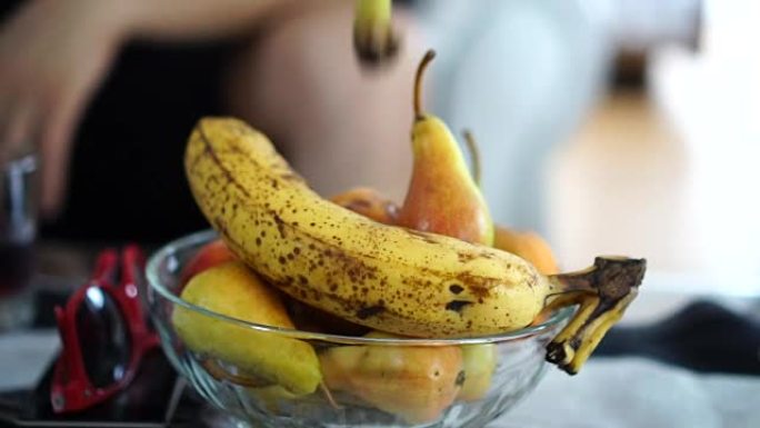 慢动作-将香蕉皮扔在一碗水果上