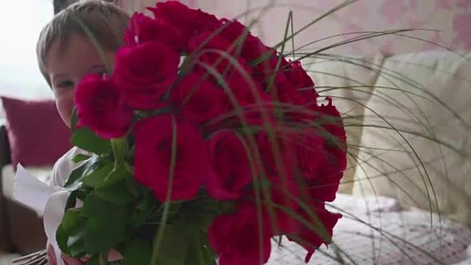 快乐宝贝捧着一大束猩红色的玫瑰花。母亲生日礼物