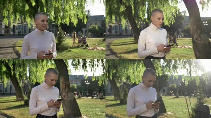年轻的非凡大胆的女孩在白天，夏天在公园里散步，在智能手机上输入信息，交流概念，思维概念