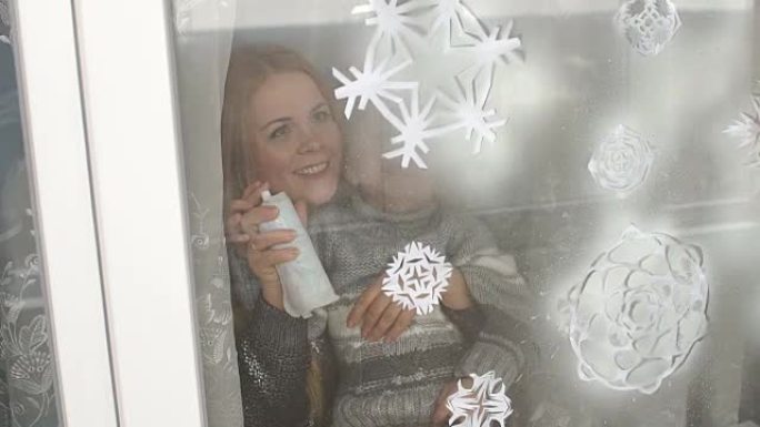 母子俩用假雪装饰窗户。