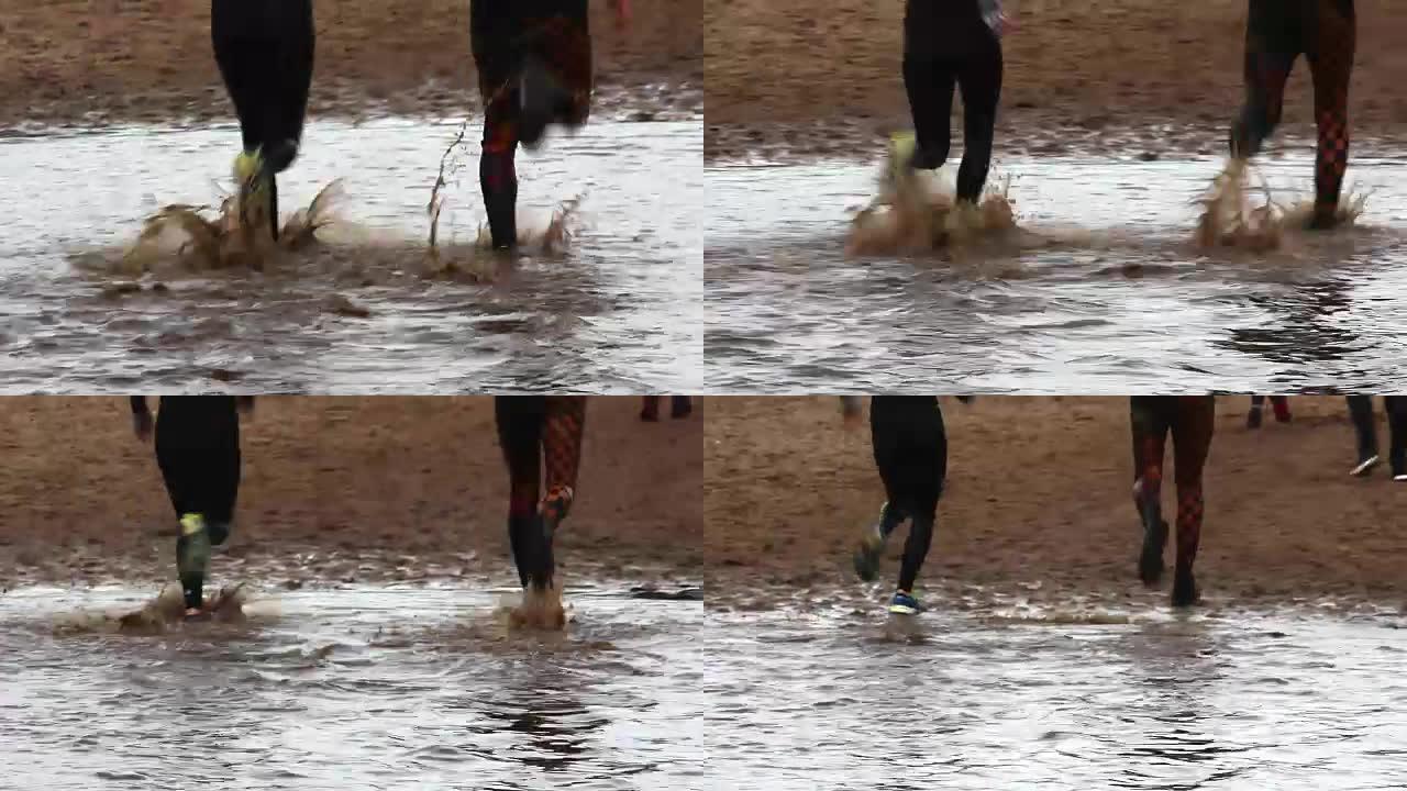 在障碍耐力赛中，在水和泥中奔跑的跑步者