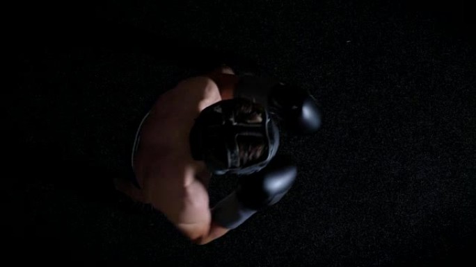 年轻的高加索人上身拳击手在防护头盔，戳刺，拳，黑色背景，顶视图50 fps