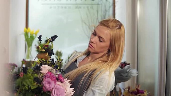 专业金发女花卉艺术家在花店安排美丽的婚礼花束。花艺、手工制作和小型企业概念。慢动作镜头
