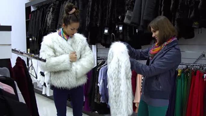两个年轻漂亮的女孩在时尚的精品店挑选衣服。女孩们仔细看衣服，检查一下。