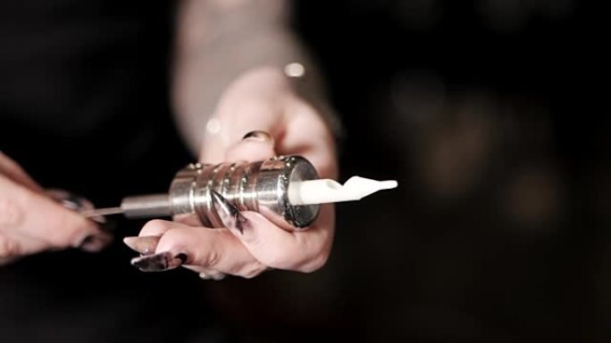 女纹身师组装一个纹身机，将一根针放在管夹内。慢动作