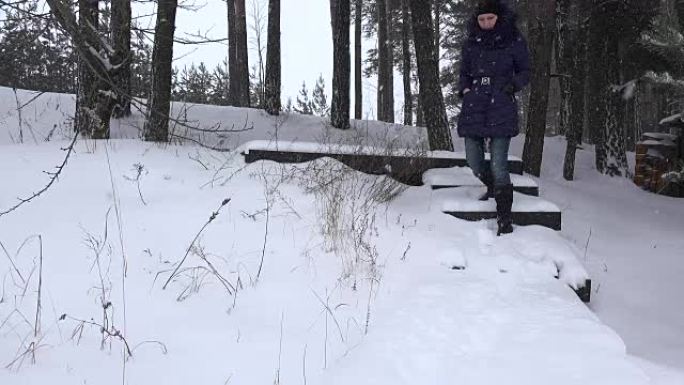 在冬季公园，女人走下积雪覆盖的楼梯。全高清