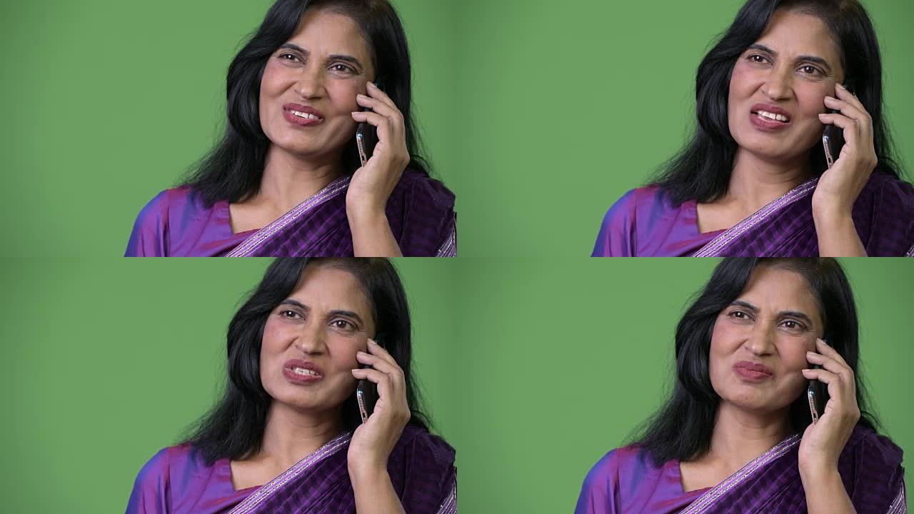 成熟快乐美丽的印度女人在思考时在电话上交谈的特写镜头
