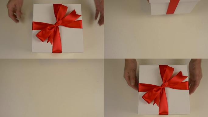 高加索人的手给红色礼品盒与金丝带蝴蝶结。手拿白色礼品盒。顶视图特写镜头。白色礼品盒。