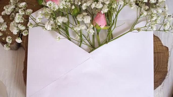 用书法笔在木制白色背景上带花的牛皮纸信封