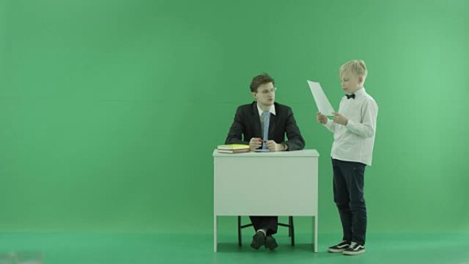 一个学生在绿屏上向老师读东西