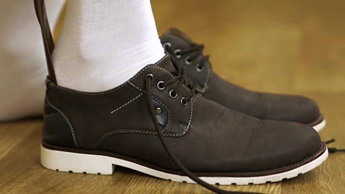 穿白袜子的男人穿鞋系鞋带。把靴子。