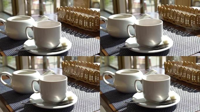 咖啡馆桌上热气腾腾的白杯茶咖啡。热饮料