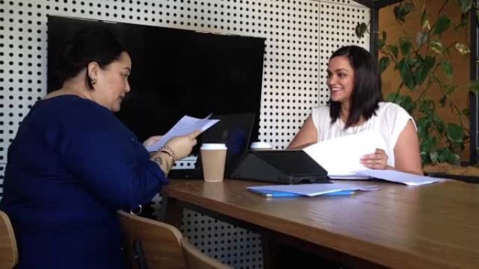 两名毛利女员工在商务会议上审阅文件
