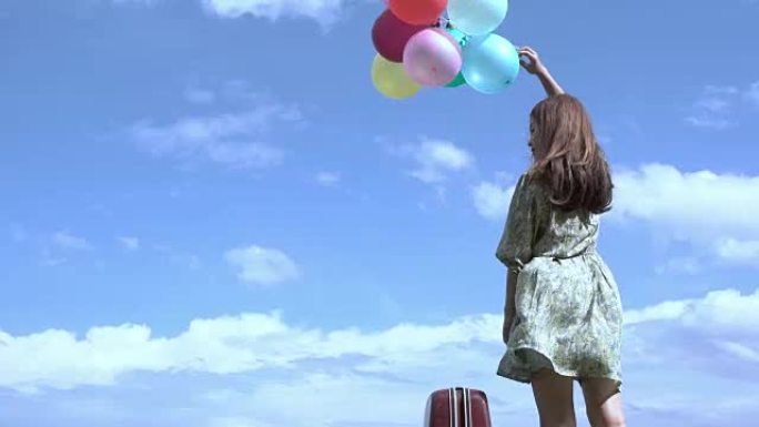 美丽的女孩在户外拿着一个气球，背景是山河。设想亚洲女孩明亮的快乐。