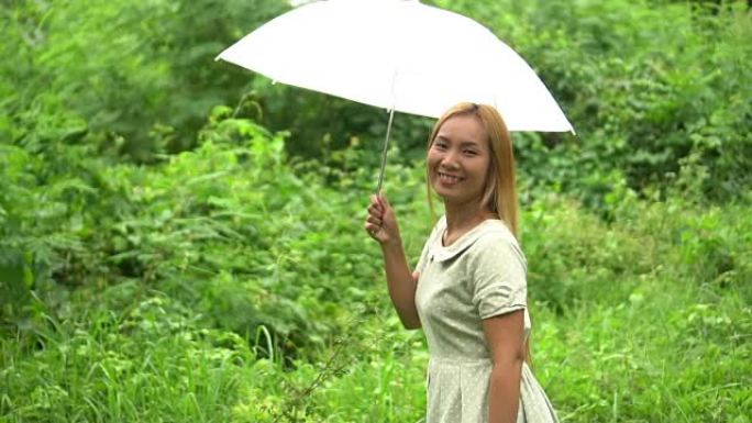 女人在雨下走路手拿着白伞