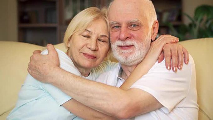 退休老年夫妇坐在沙发上拥抱的肖像。概念永无止境的伟大爱情