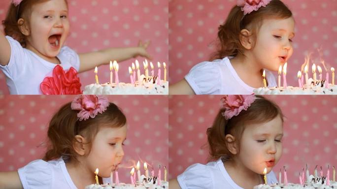 可爱的快乐的孩子许愿，并在聚会上吹灭生日蛋糕上的蜡烛。有趣的小女孩。儿童假期的概念。3年，粉色背景