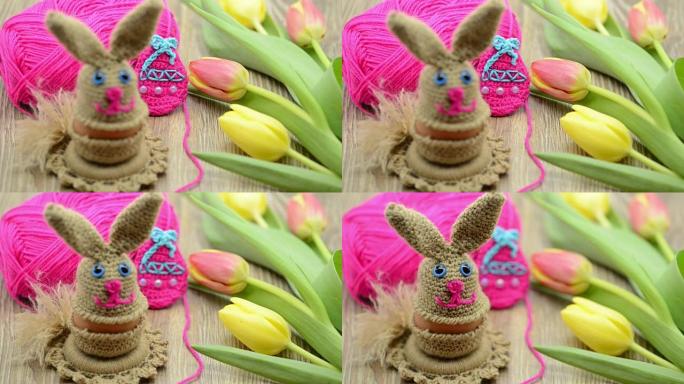 羊毛钩针复活节兔子蛋杯。背景为新鲜郁金香和羊毛球