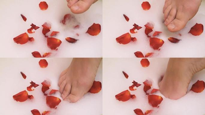 泡沫中的雌性脚和红玫瑰的花瓣