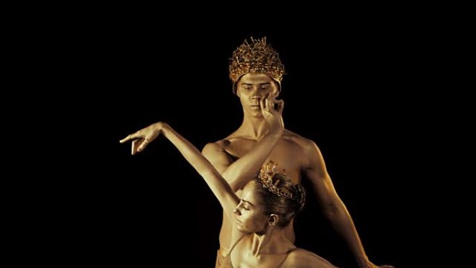 专业情感芭蕾舞者在黑烟舞台上加冕，由性伴侣国王和王后用金色人体艺术表演。高级时尚。闪亮的金色皮肤