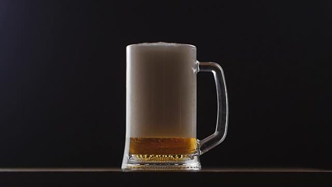 啤酒倒入黑色背景的玻璃中。慢动作