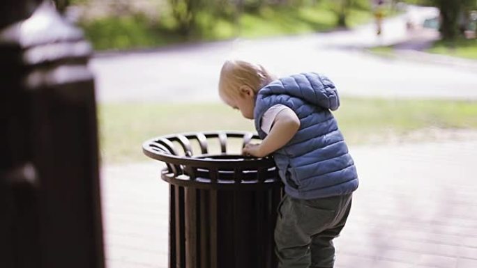 金发小男孩在公园玩垃圾。