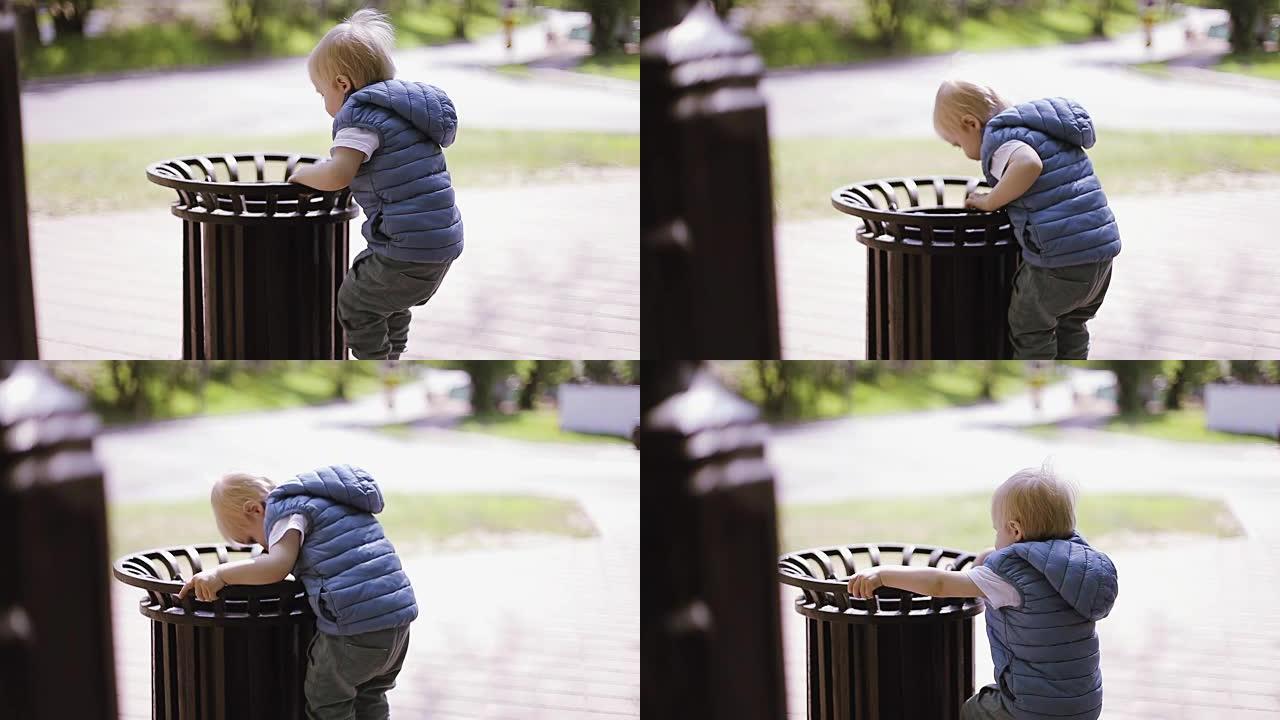 金发小男孩在公园玩垃圾。