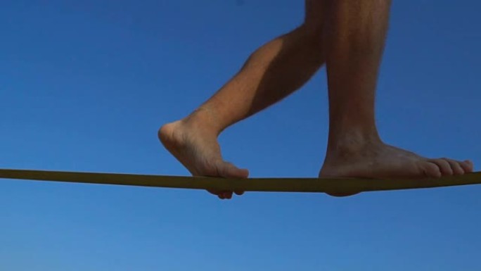 在极限运动节上，男人的腿在绳子上行走。懒人步行