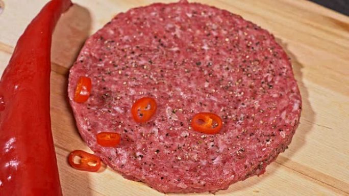 库克为汉堡制作肉质奖章。倒入香料胡椒和盐。肉大理石牛肉放在食物木板上，用于切割和红辣椒辣椒。