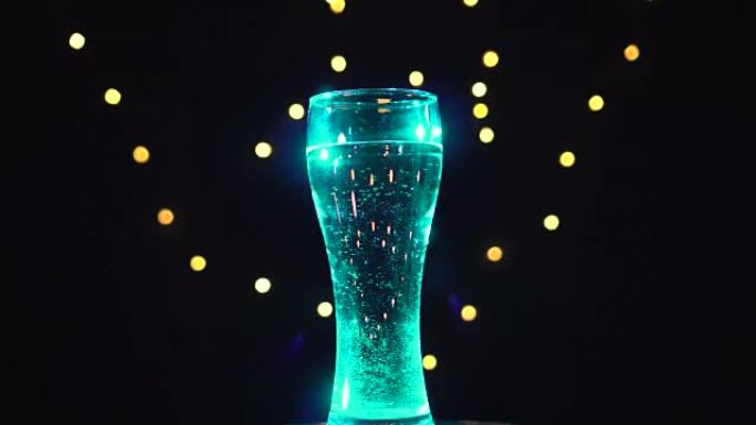 天蓝色灯光下的一杯水正在转动。绿松石杜松子酒鸡尾酒。酒吧概念