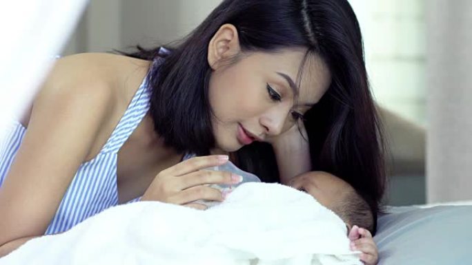 年轻美丽的亚洲妈妈关心和玩她的宝宝