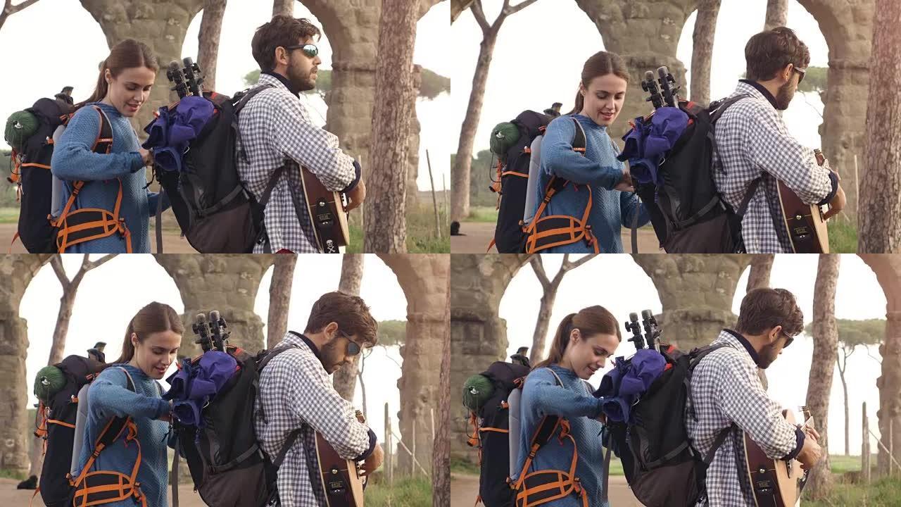 年轻夫妇背包客游客在日出时用吉他和睡袋慢动作steadycam搜索罗马parco degli acq