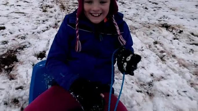 女孩在解冻的雪上雪橇