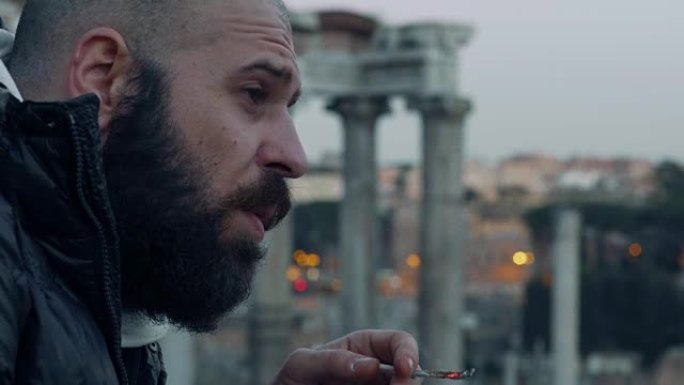 英俊的秃头男人独自抽烟，观察城市