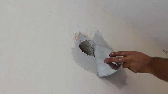 工人在油漆前在墙壁插座周围涂上脱脂涂层材料