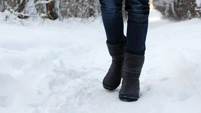 一个穿着靴子的女人在雪地里冻腿的特写镜头。
