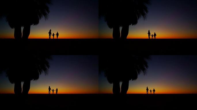 热带日落，棕榈树剪影在海洋海滩，女人，男人和孩子沿着海岸行走