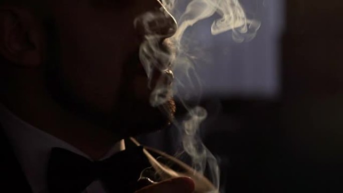 男人用人造光在黑暗中抽雪茄。