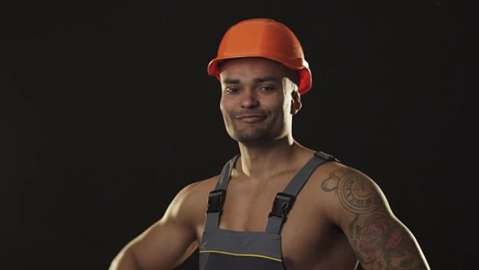 肌肉撕裂的非洲男性建筑工人在工作服和安全帽伸缩肌肉