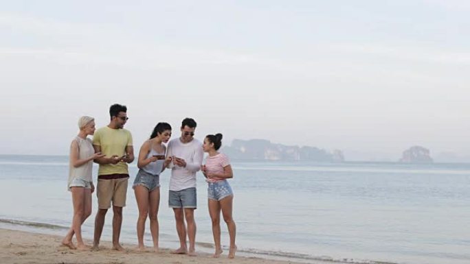 人们在海滩上使用手机智能手机，年轻游客在线组网