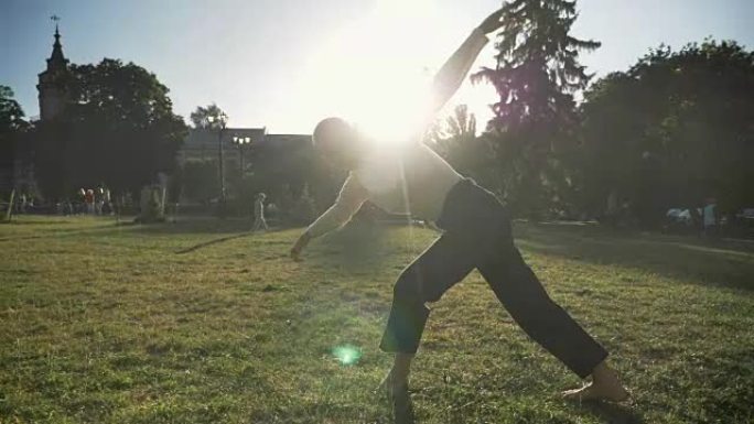 年轻的非凡大胆的女孩在夏天的白天在公园的草地上跳舞，看着镜头，运动概念，底部视图